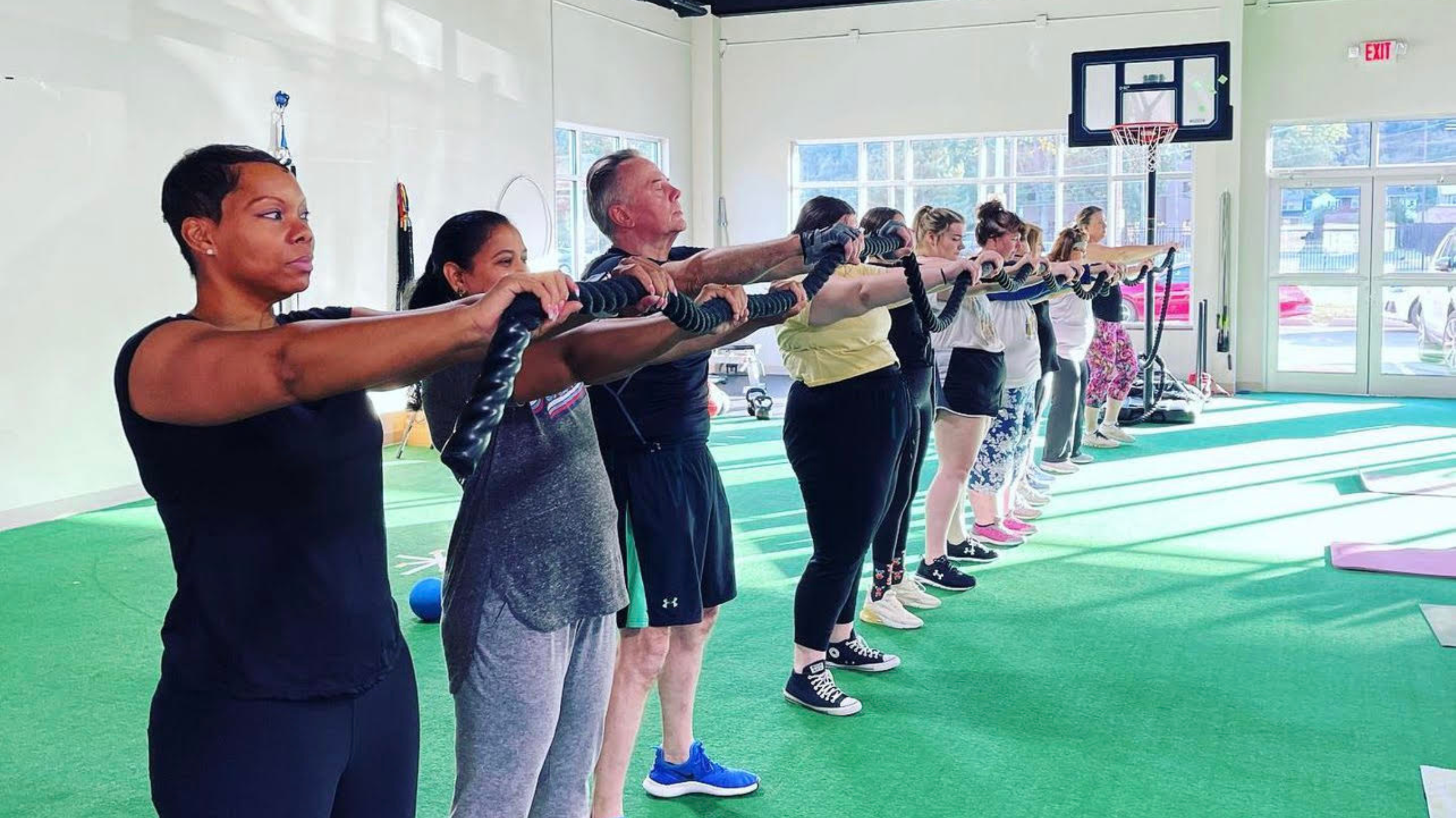 People standing in a row and holding up a black rope.